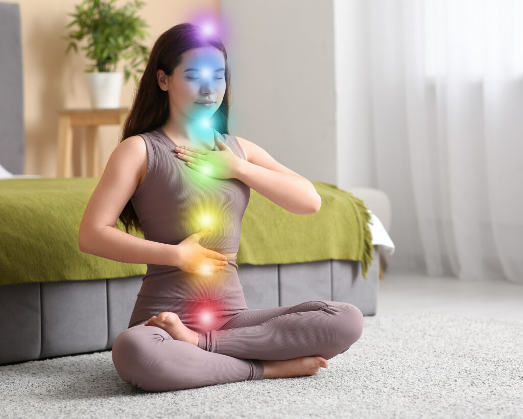 Anahata Chakra Meaning: All About the Heart Chakra Powers Woman sitting in lotus pose with glowing chakra points aligned along her body, focusing on the heart chakra during meditation.