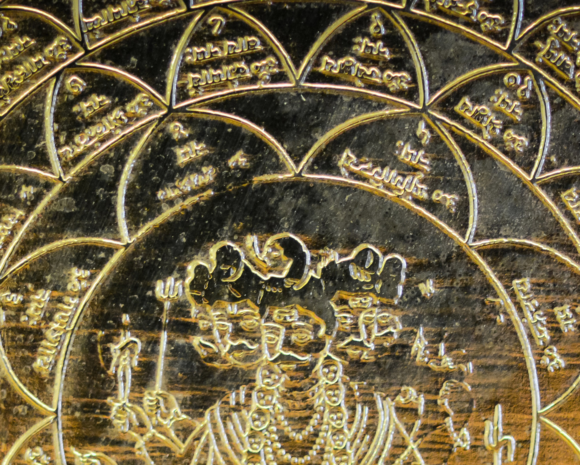 Gold Chakra, aka 10 Chakra: All You Need to Know! Detailed close-up of a golden engraved spiritual mandala featuring symbolic figures and sacred geometric patterns.