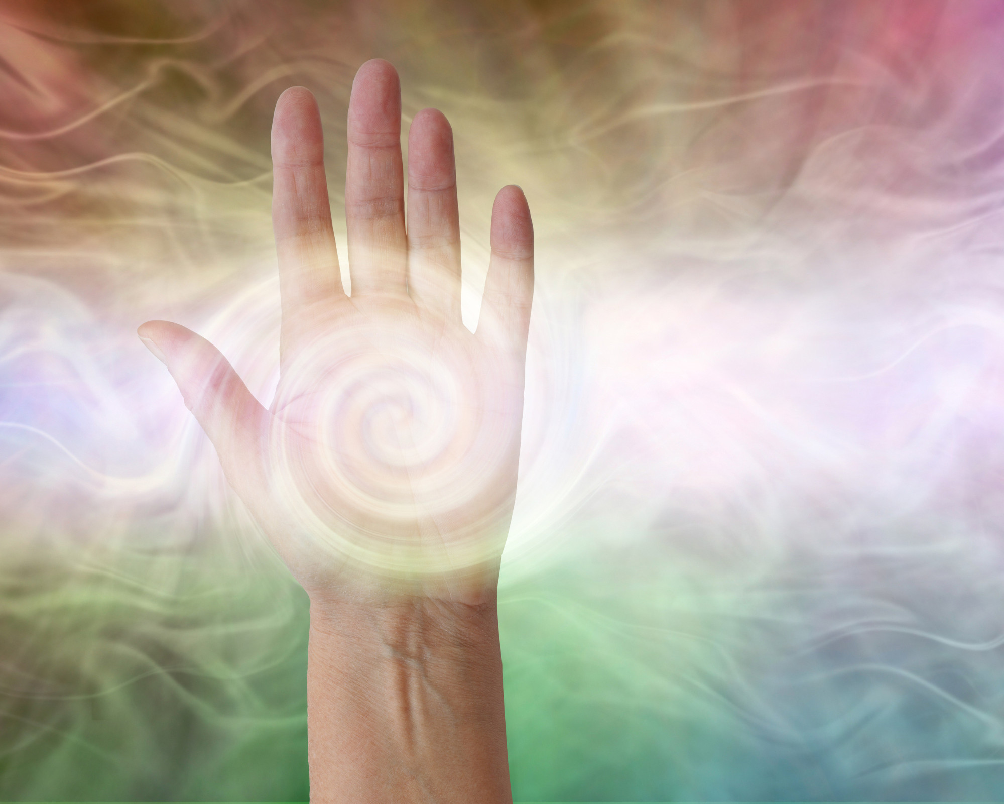 12th Chakra (Stellar Gateway Chakra): All You Need to Know! A hand with a swirling spiral of light in the palm, surrounded by soft rainbow colors, representing energy healing and chakra activation.