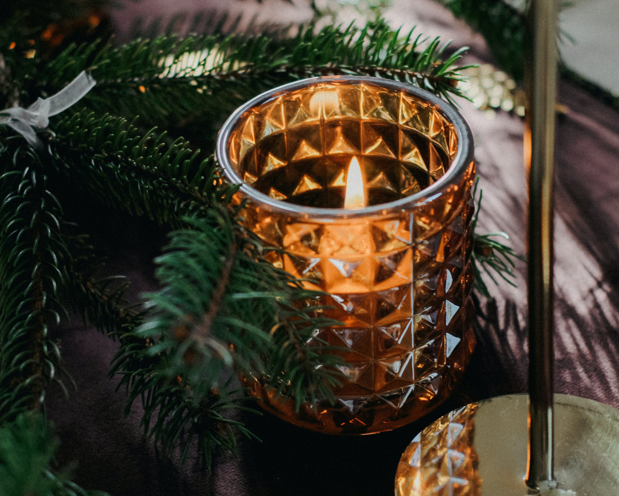 How to Celebrate Yule? Bring Yule Winter Solstice Into Your Life! A glowing candle surrounded by fresh evergreen branches, showing how to celebrate Yule through light, warmth, and honoring the return of the Sun.