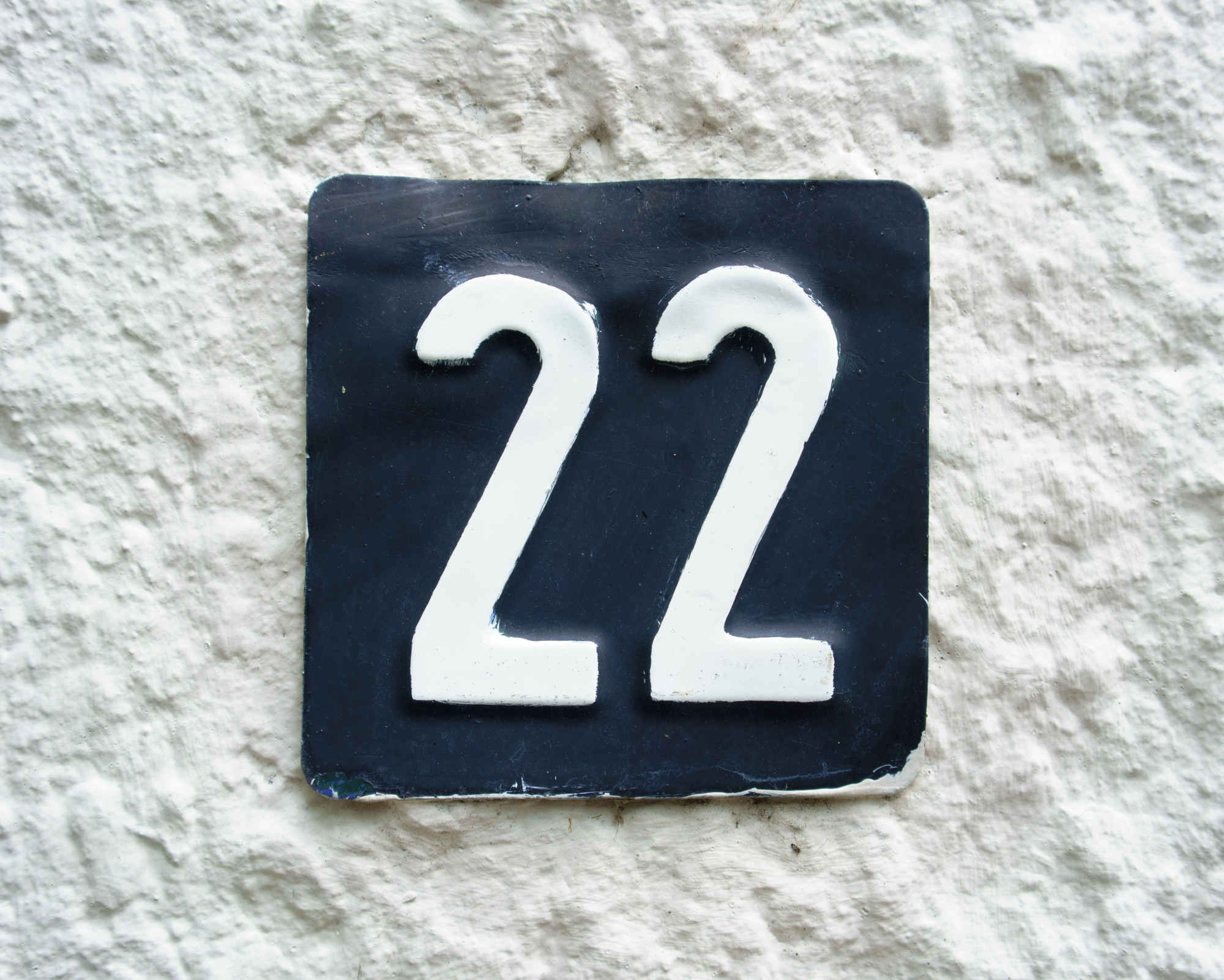 Angel Number 22: Discover Everything About This Master Number! Black and white house plaque displaying the number 22, symbolizing repeated encounters with Angel Number 22.