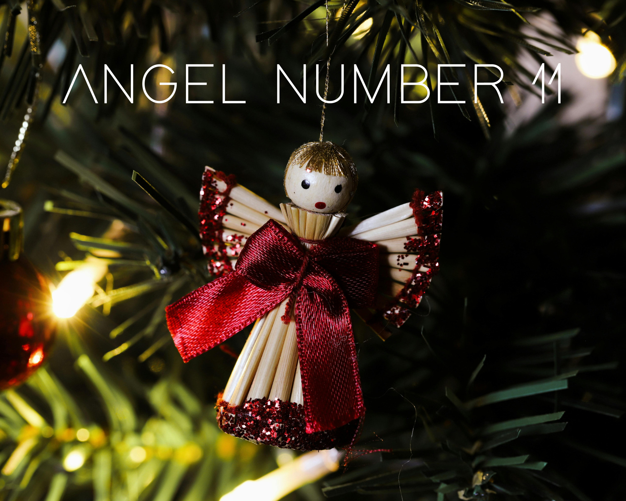 11 Angel Numbers Christmas tree close-up featuring a wooden angel ornament with the text angel number 11 glowing against festive lights.