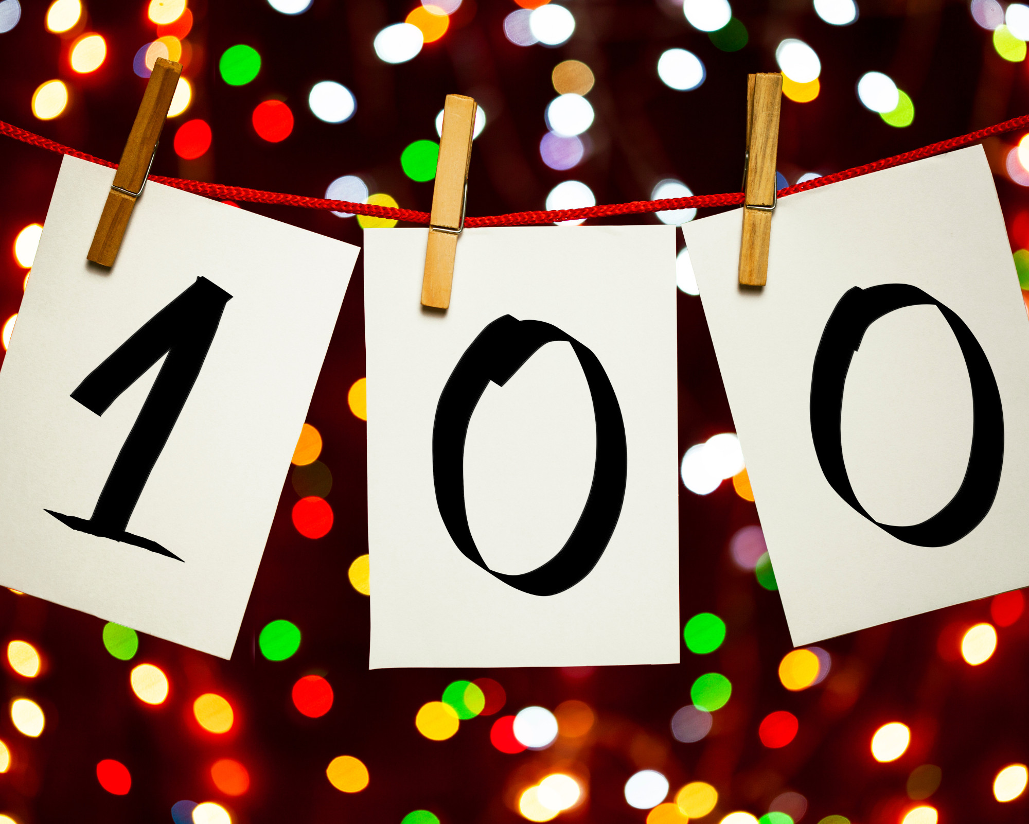 100 Angel Number 100 Creative display of the 100 angel number shown as handwritten digits clipped on a string with colorful lights in the background.