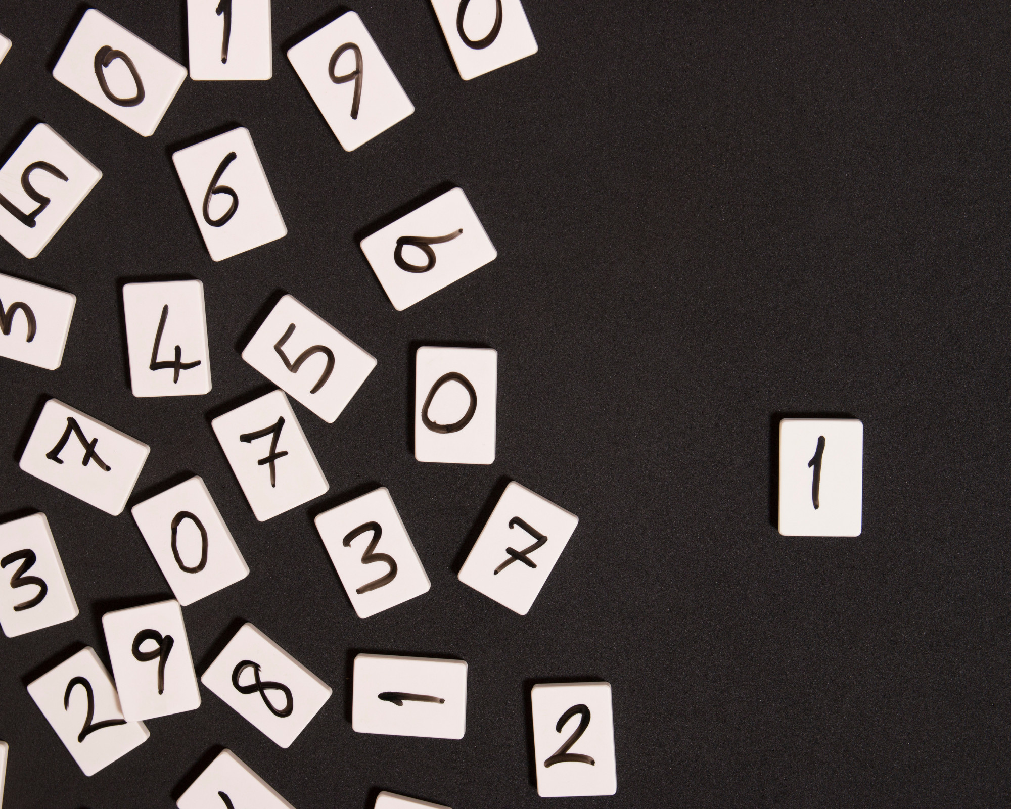 Single Digit Angel Numbers Scattered white number tiles on a dark surface, highlighting the simplicity and clarity of single digit angel numbers.