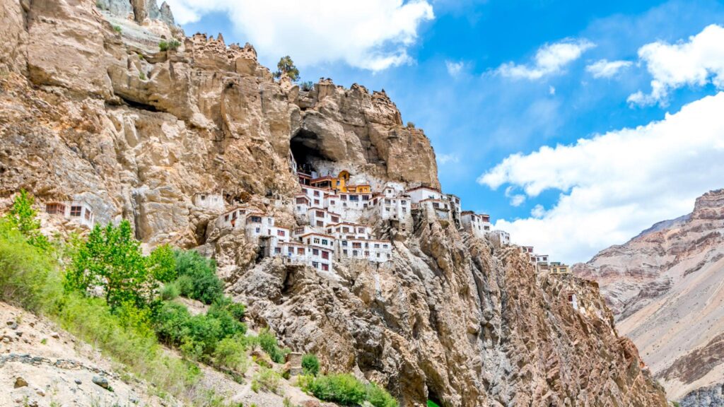 The Silence Between the Monasteries: What Spiti Valley Taught Me About Stillness Phuktal Monastery built into a cave in a towering cliff, with white and ochre buildings clustered against the rock face overlooking a remote mountain valley.