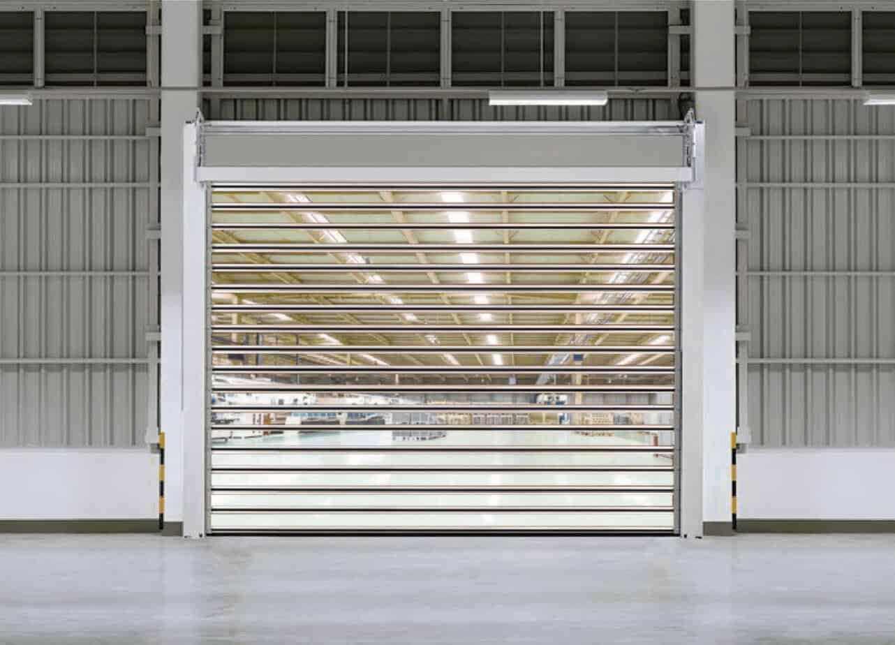 High-speed industrial roller shutter door installed in a warehouse for security and climate control. Durable steel construction with sleek horizontal slats for easy access and robust protection.