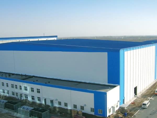 High-capacity industrial warehouse building with blue and white exterior, featuring secure doors and ample space for storage and logistics operations.