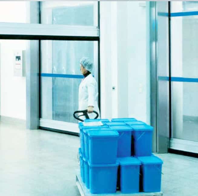 High-security automatic sliding glass door in a clean facility with a worker and blue storage boxes.