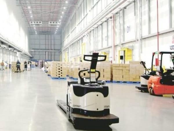 Efficient warehouse with automated material handling vehicles operating amidst stacked boxes and industrial shelving. Modern logistics and supply chain solutions showcased in a spacious, well-lit facility.