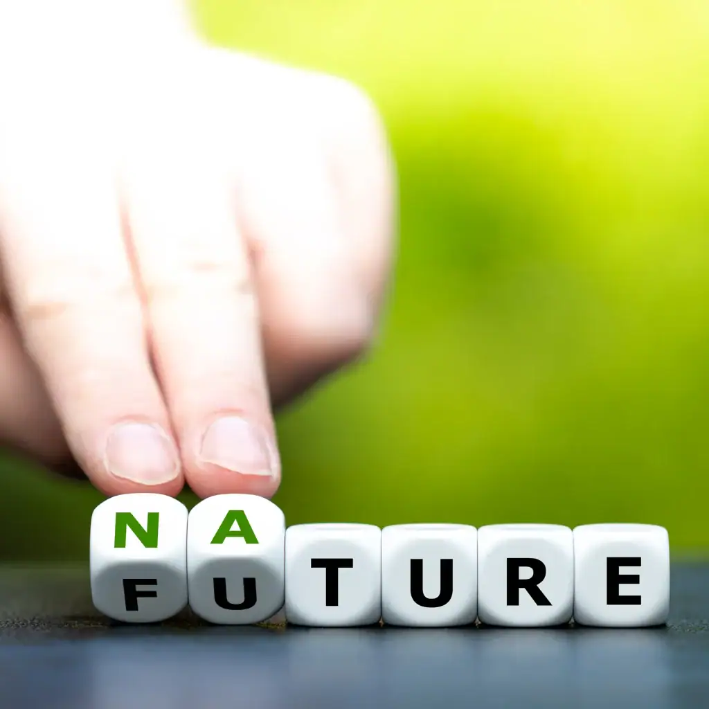 Hand arranging letter blocks that combine the words nature and future against a green background