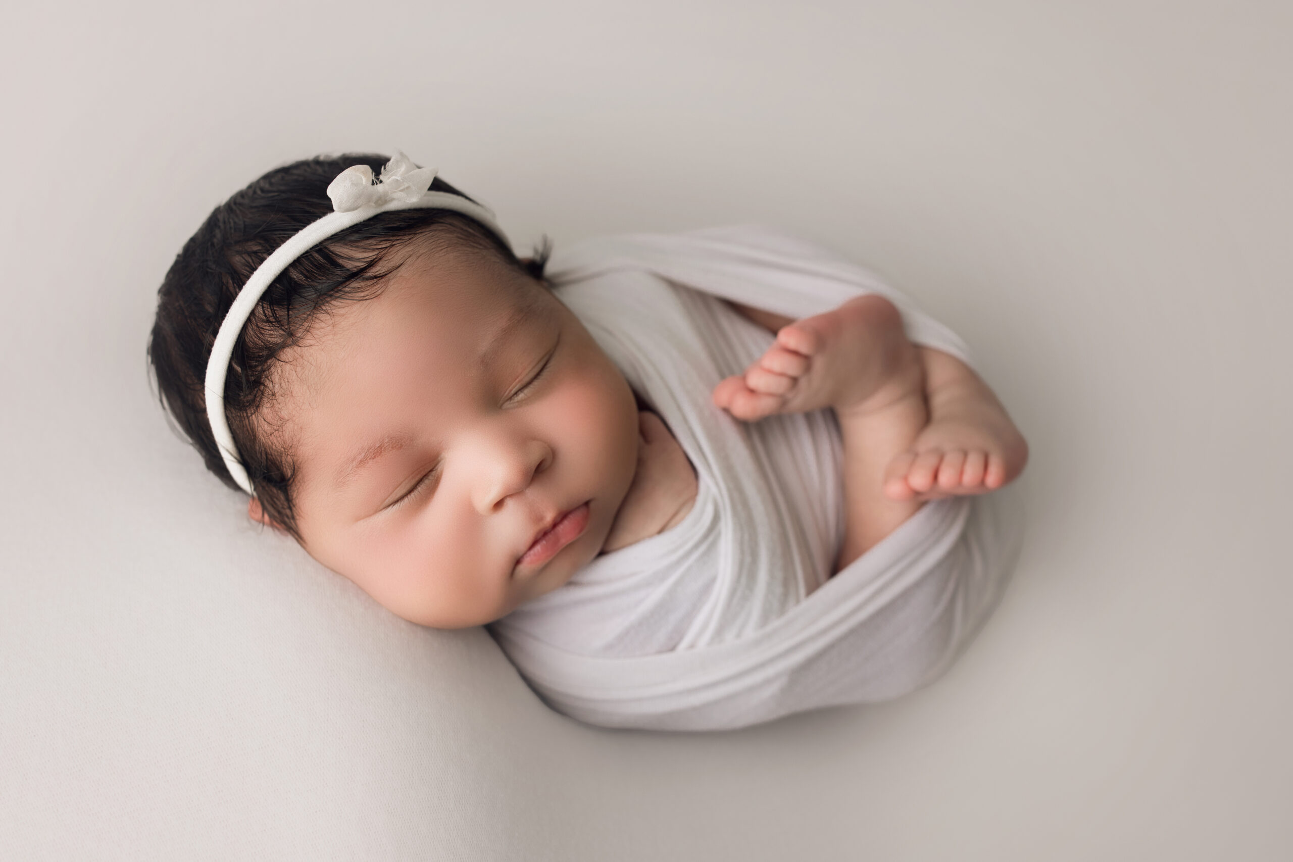 Newborn Baby Girl wrapped in white with a white bow