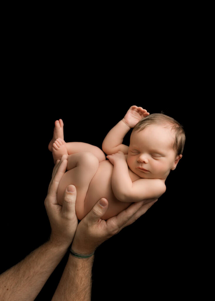 A newborn baby is held in daddy's hands
