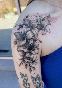 Lilies and floral tattoo on shoulder, black ink, detailed artwork by SASH TATTOO.