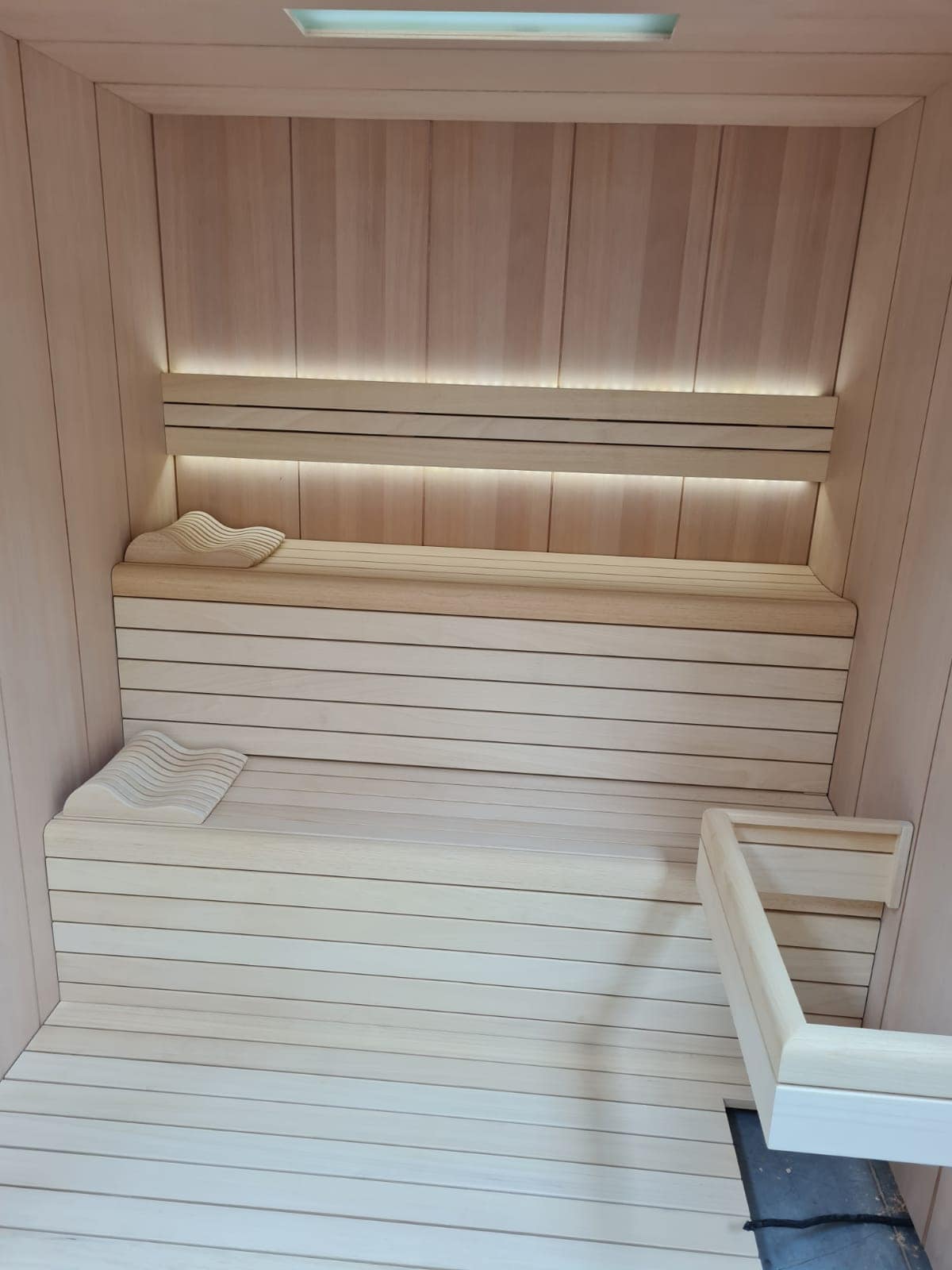 Relaxing wooden sauna interior with bench seating, soft lighting, and a towe.