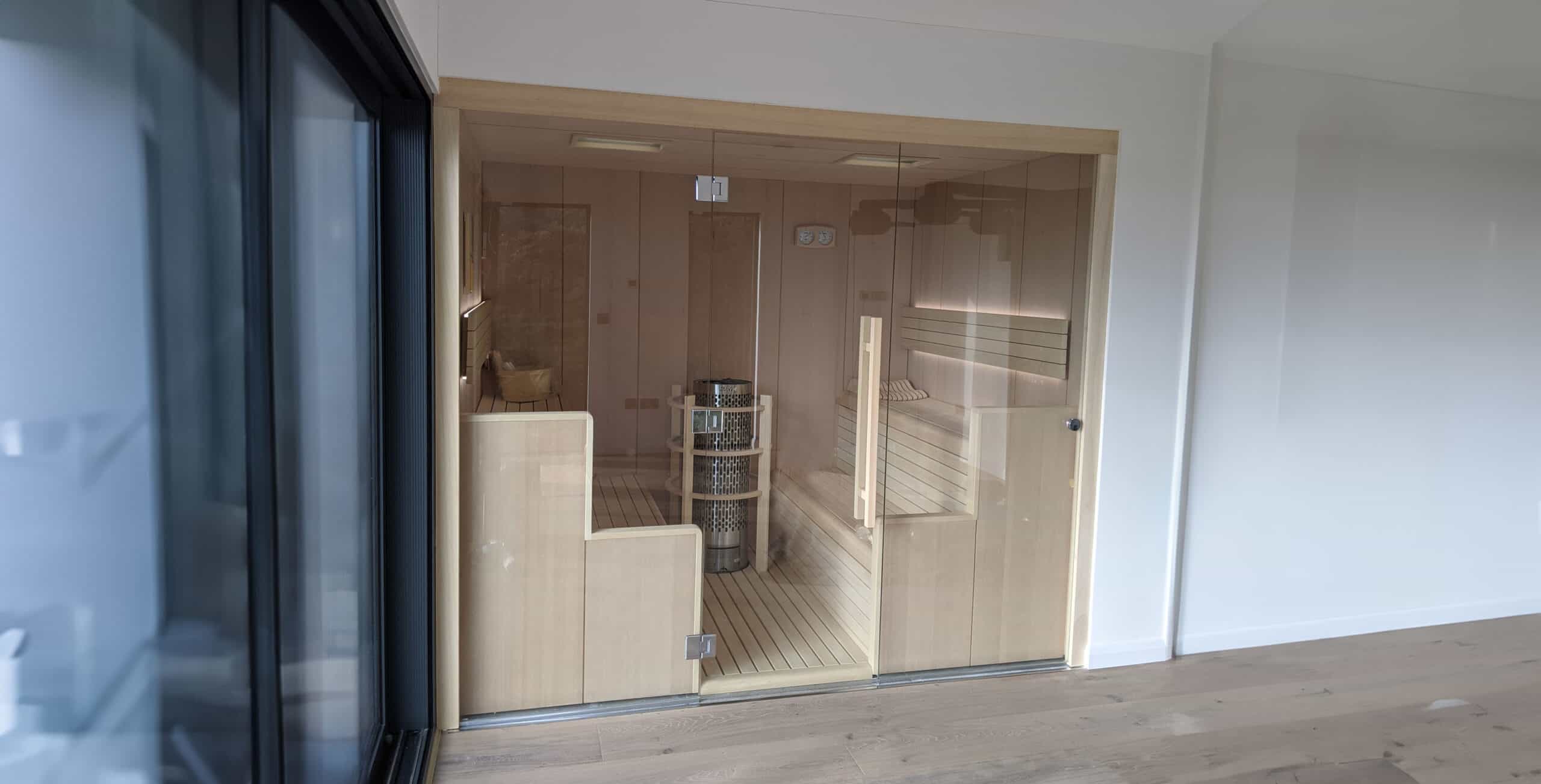 Modern sauna with glass door and wooden interior.