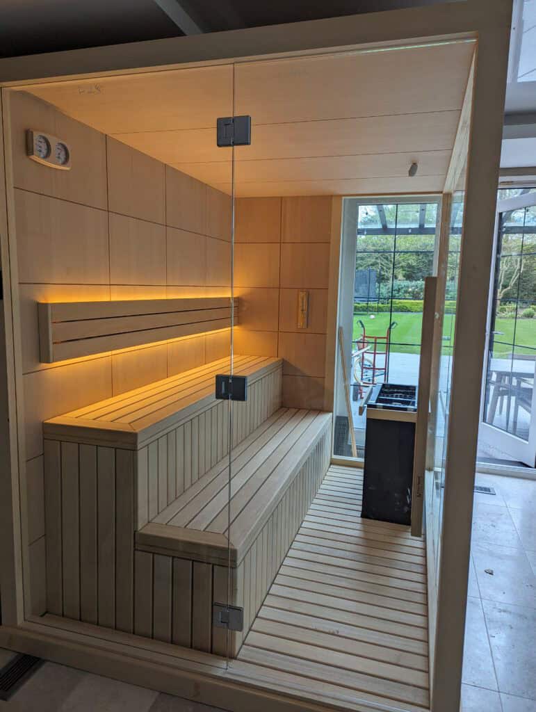 Relaxing wooden sauna with glass door and outdoor view, featuring ambient lighting and modern design,