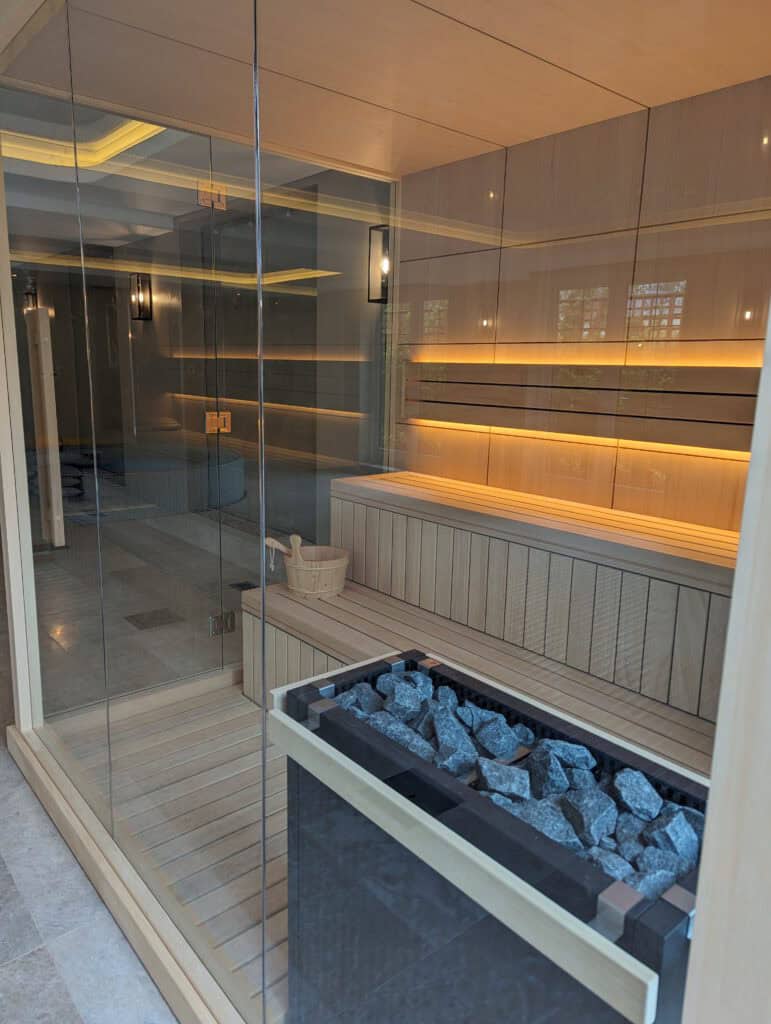 Relaxing modern sauna with glass walls, wooden interior, and heated stones