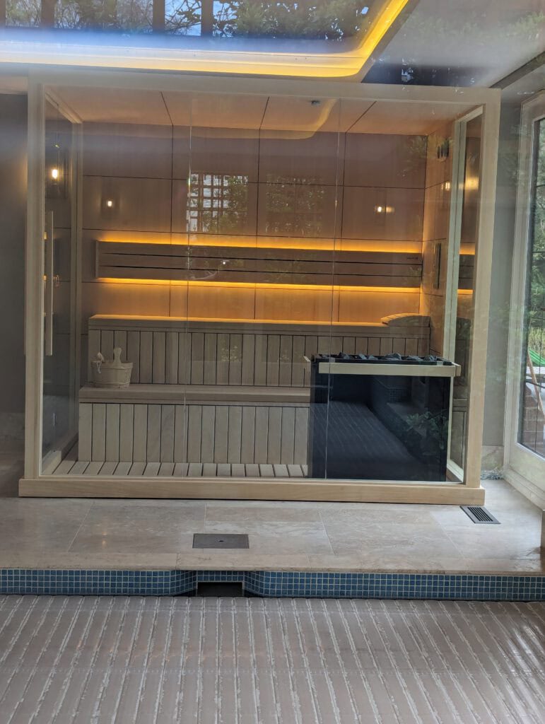 sauna with modern interior design, warm lighting, and glass walls.