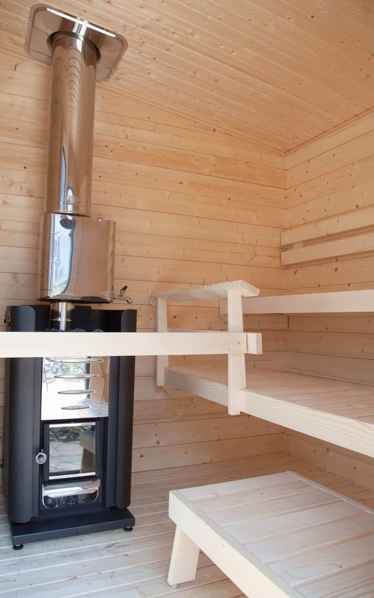 A modern indoor sauna with wooden benches and a wood-burning stove, designed for relaxation and wellness.