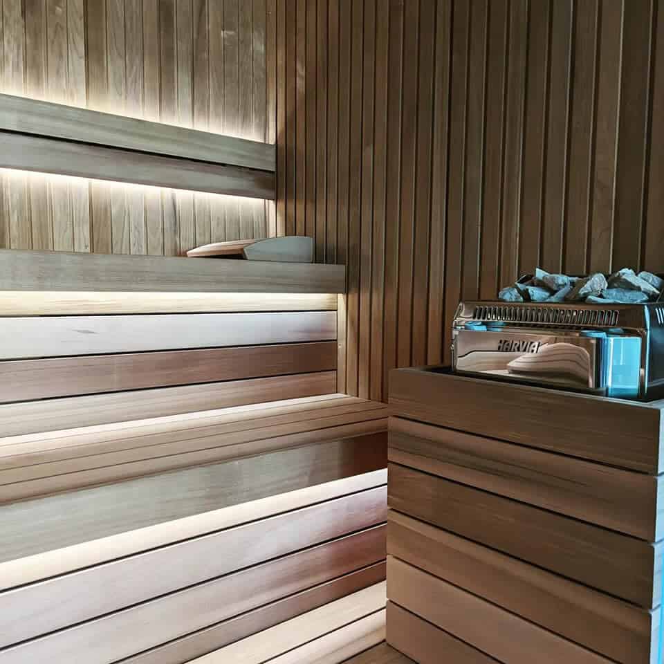 Relaxing wooden sauna interior with benches and a heater, showcasing premium craftsmanship and natural materials for an authentic wellness experience.