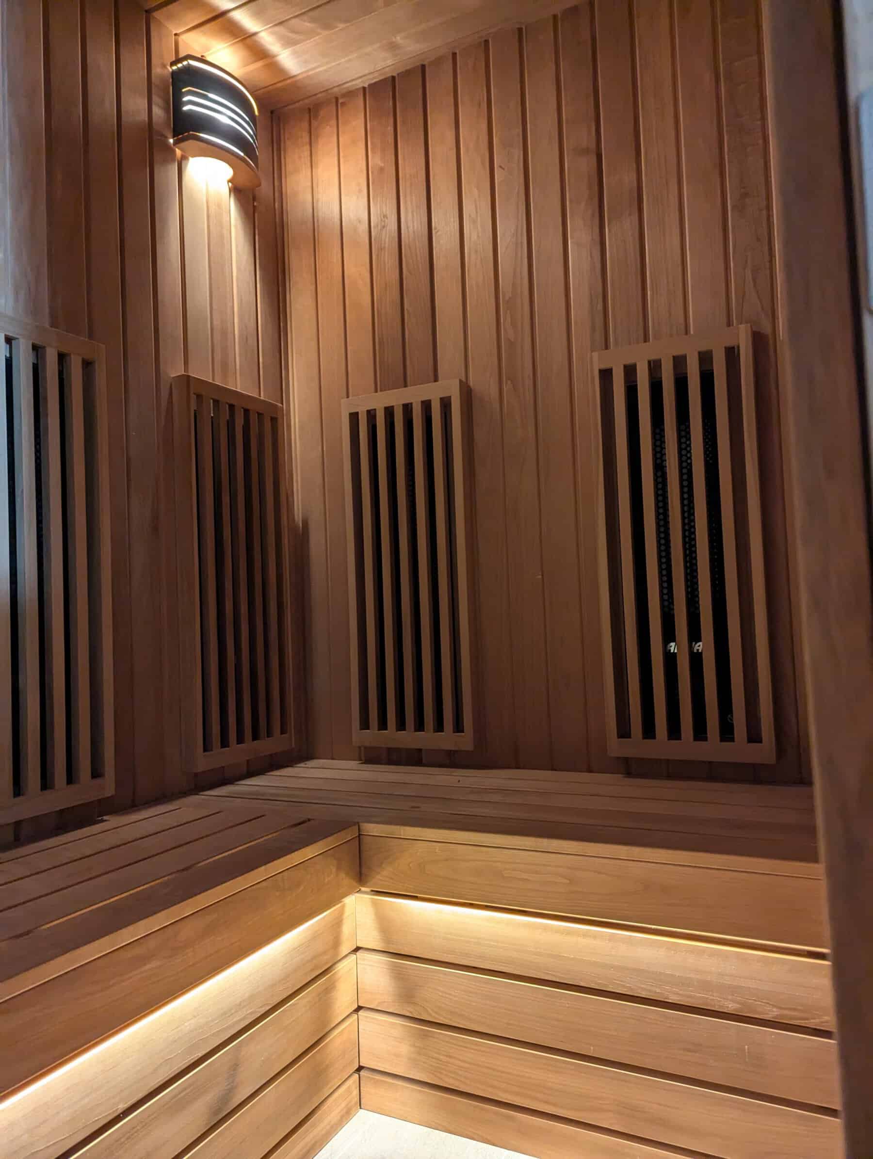 Relaxing wooden sauna interior with warm lighting, featuring slatted wooden panels and benches
