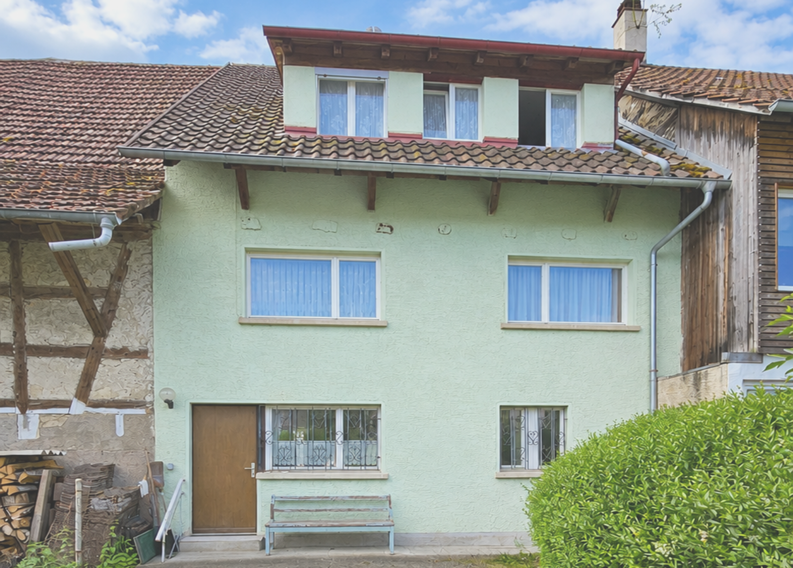 Gemütliches Mehrfamilienhaus mit grünem Fassadenanstrich und Garten.