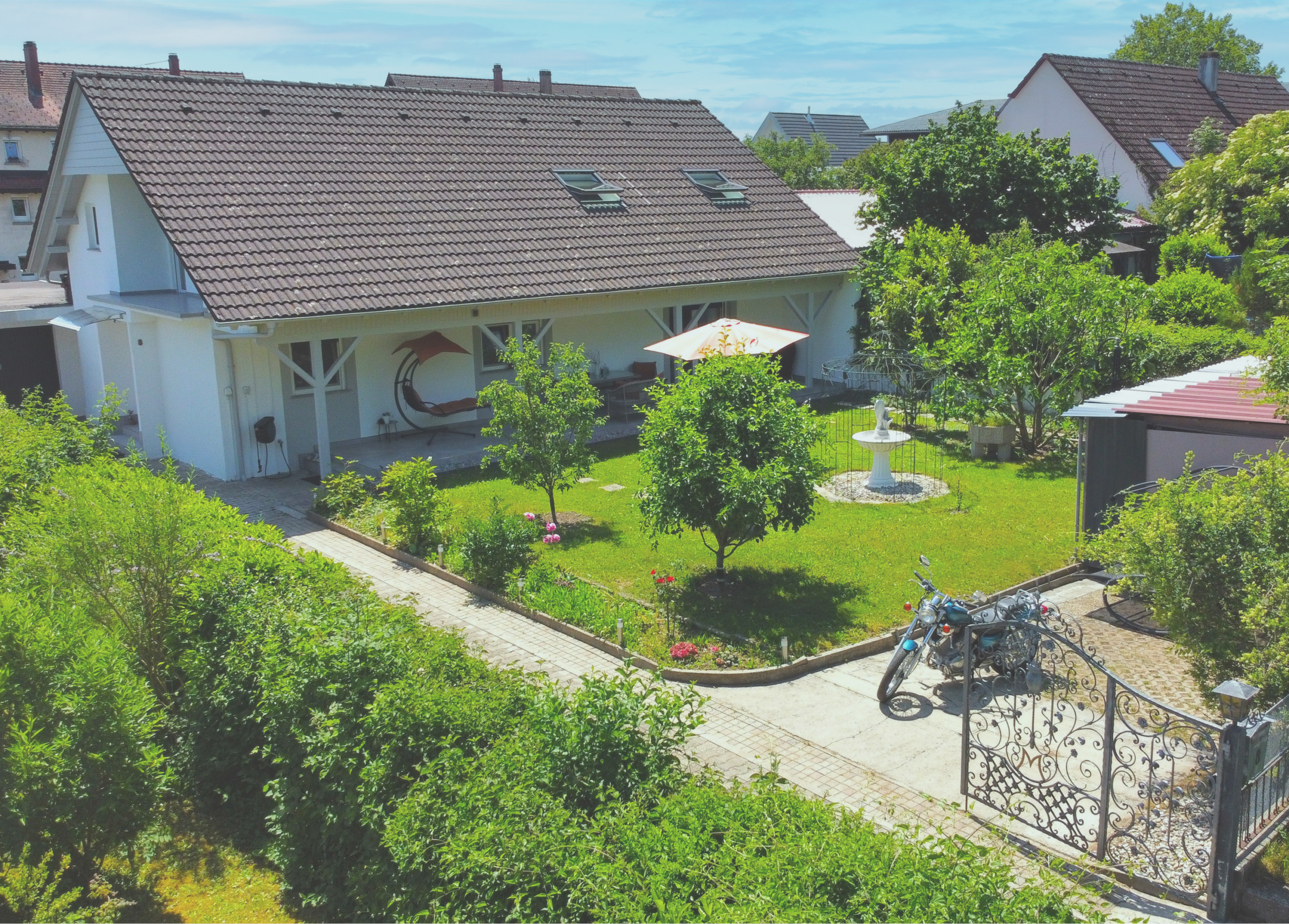 Häuser im Grünen mit Garten, Bäumen und Wasserbrunnen bei Schlatter Immobilien.