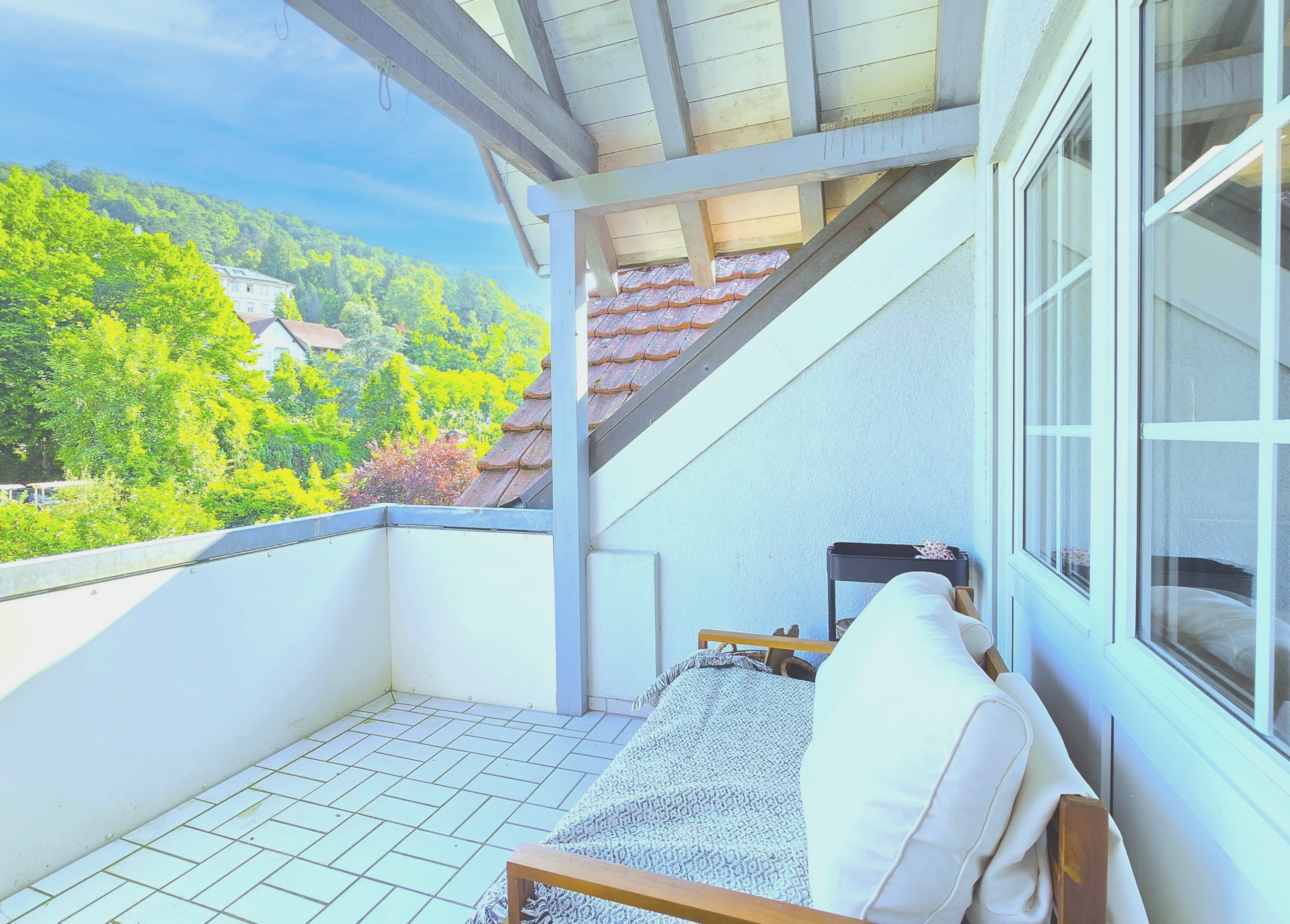 Balkon mit Sitzgelegenheit und Blick auf grüne Landschaft.