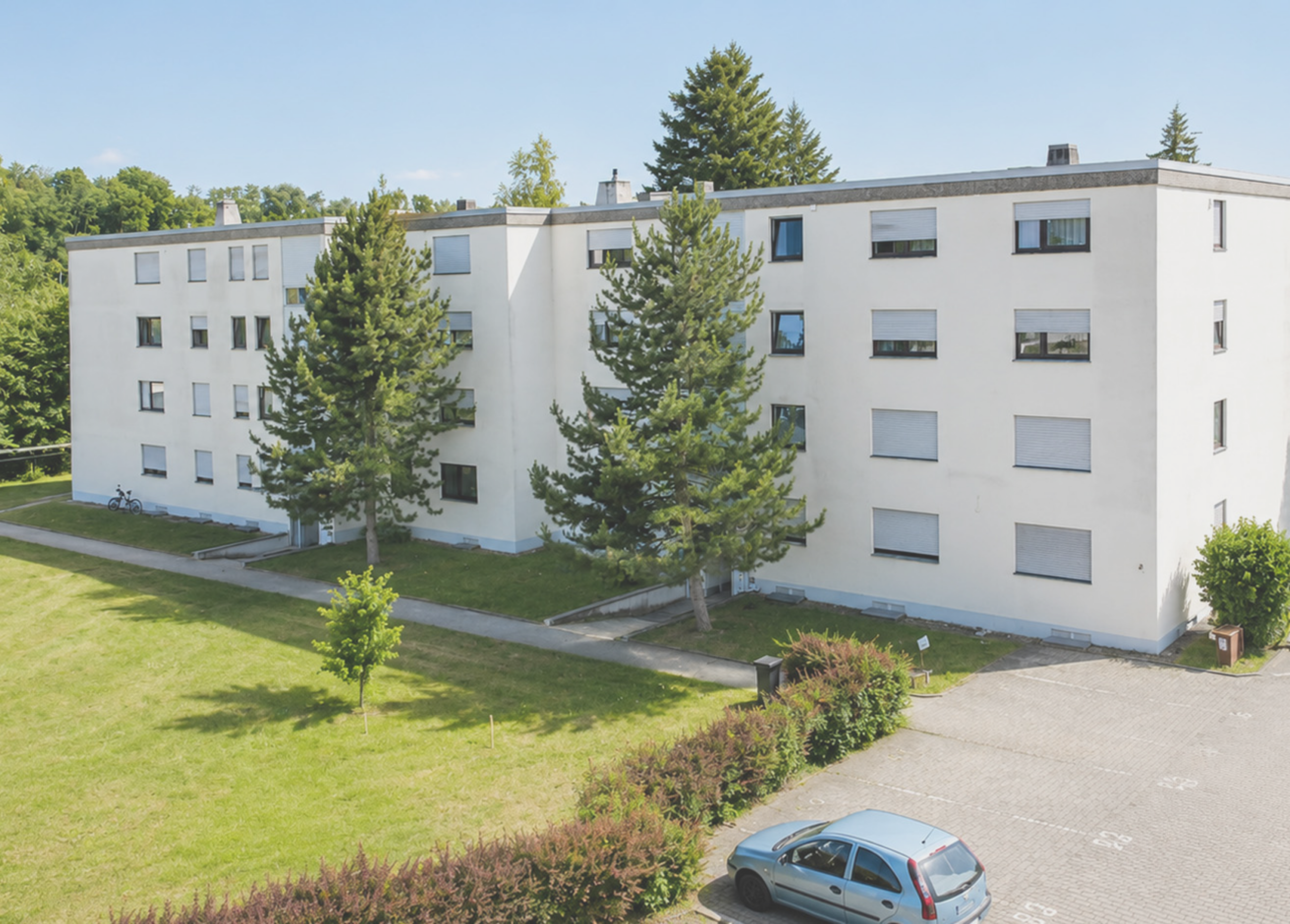 Modernes Mehrfamilienhaus mit Grünflächen und Parkplätzen.
