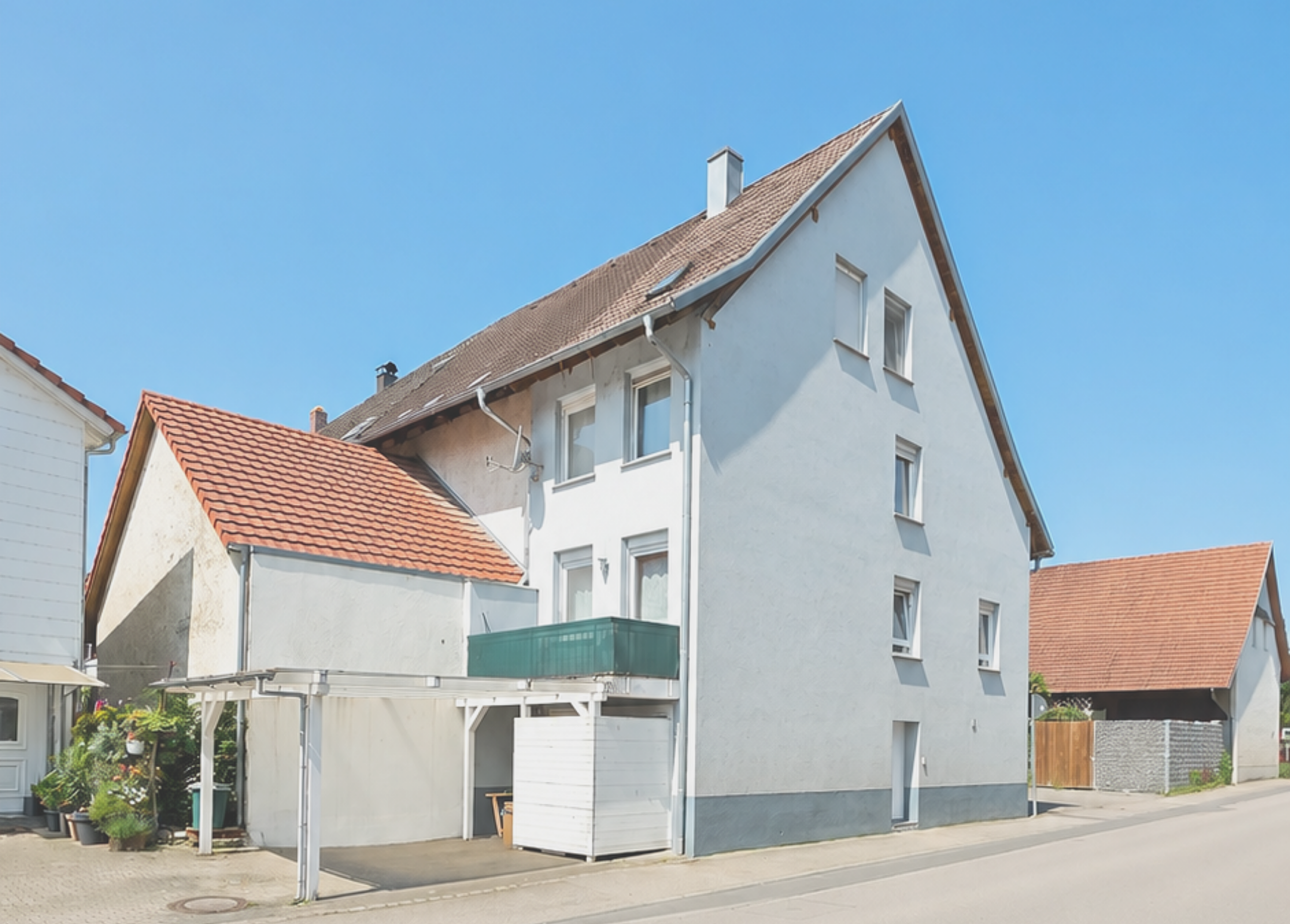 Mehrfamilienhaus in Deutschland mit weißer Fassade und rotem Dach.