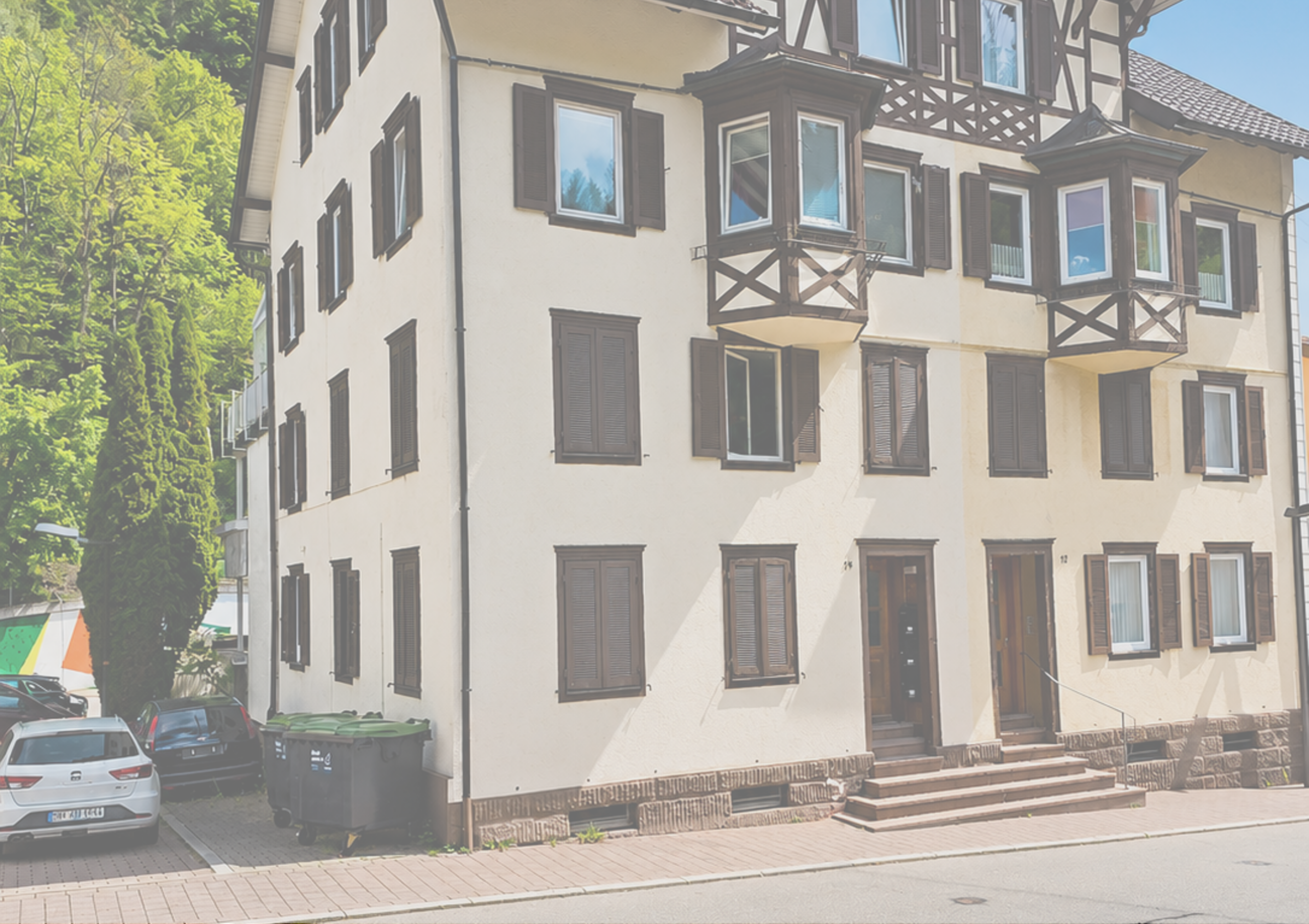 Mehrfamilienhaus mit weißen Wänden und dunklen Fensterläden in Deutschland.