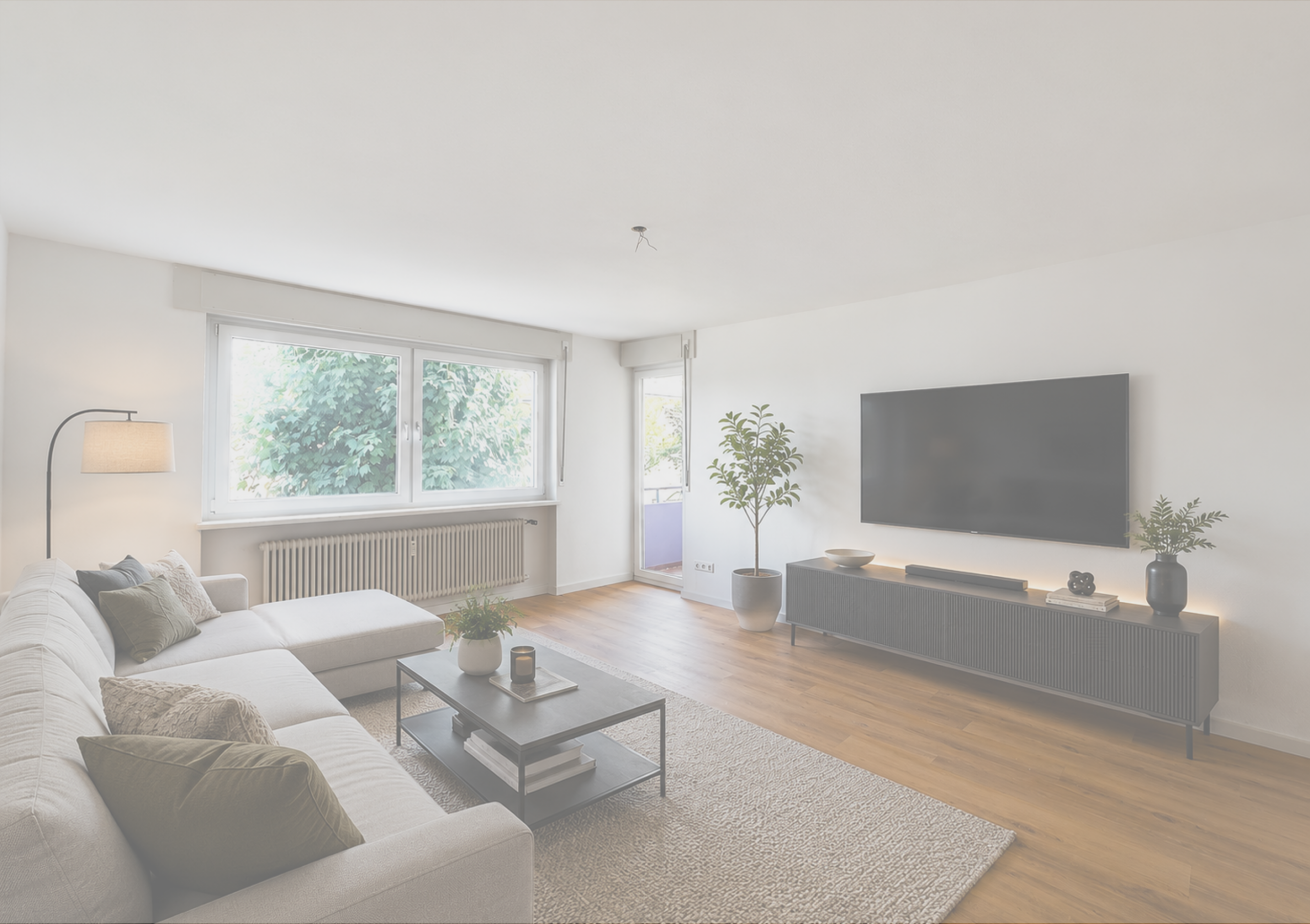 Helles, modernes Wohnzimmer mit Sofa, TV und großen Fenstern.