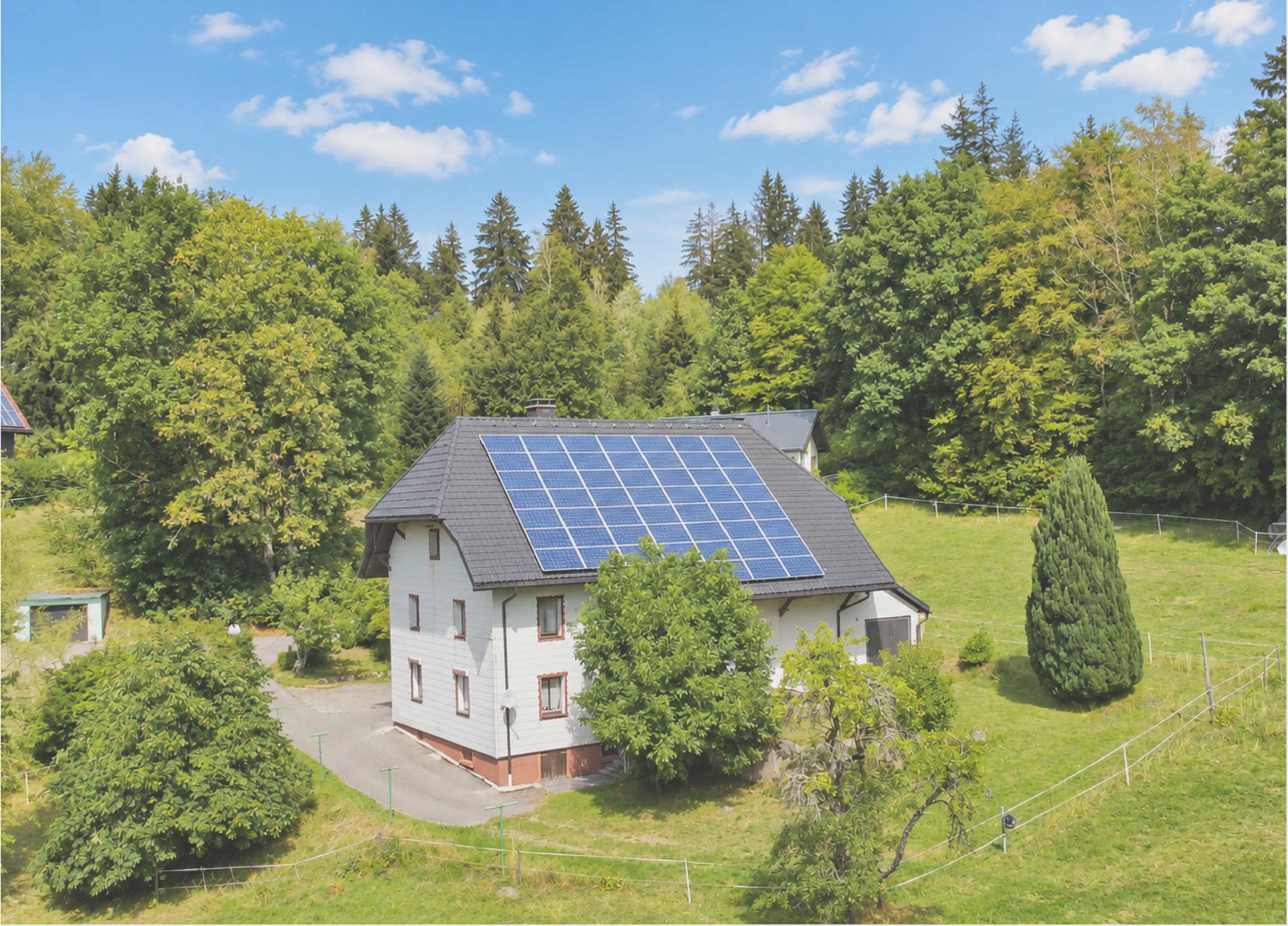 Haus mit Solaranlage auf dem Dach in grüner Umgebung.