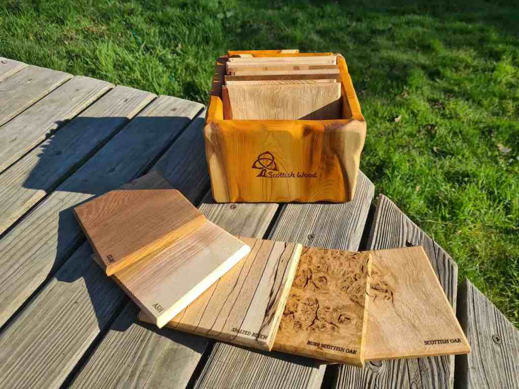 Samples of Scottish hardwood timber species, arranged in front of a handmade yew container as a gift for Prince Charles from the Storm Arwen Steering Group