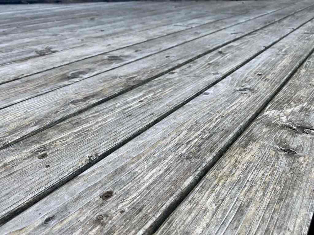 Weathered larch decking that has turned silver grey after years of exposure