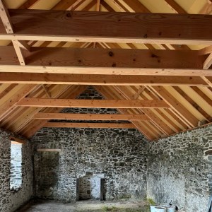 Indoor view of a new roof with thick beams over an old stone walled cottage