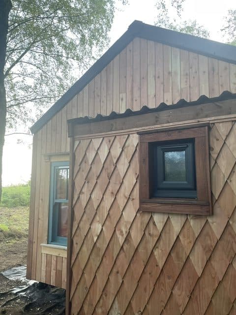 Hut in the woods clad with larch shadow gap cladding and larch shingles