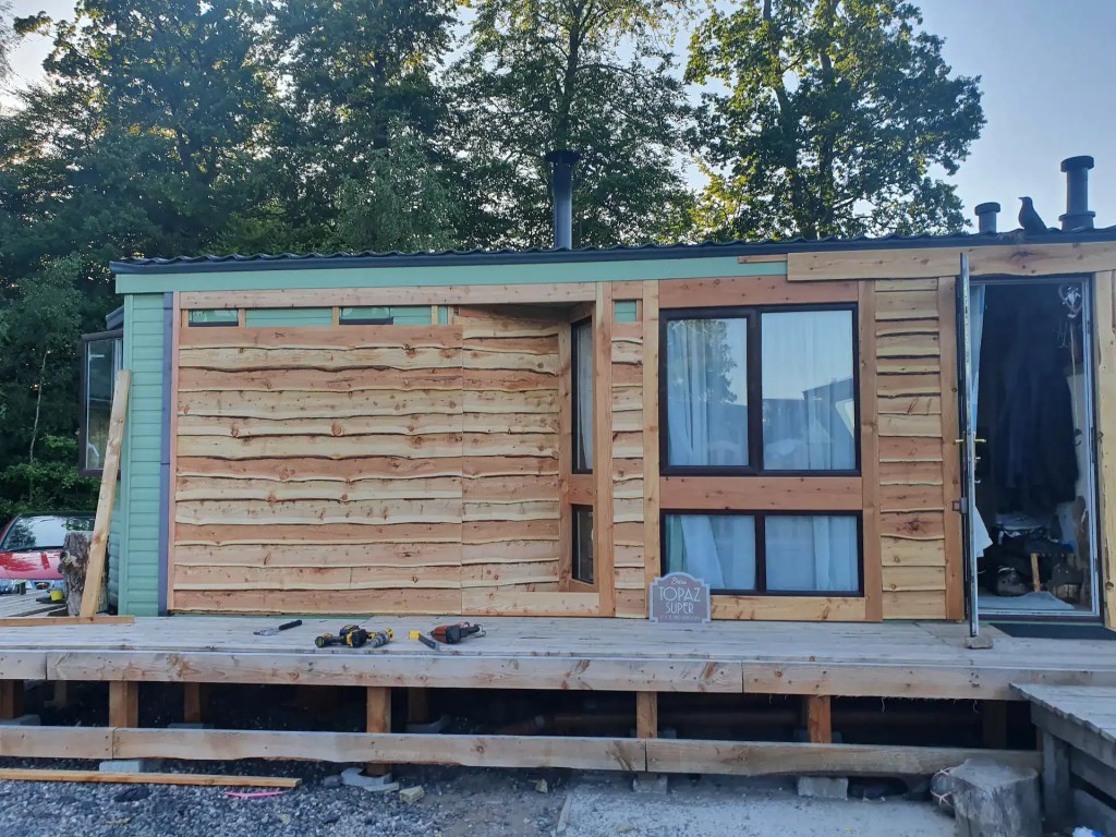 Outside of caravan that is in process of being covered with larch waney edge cladding