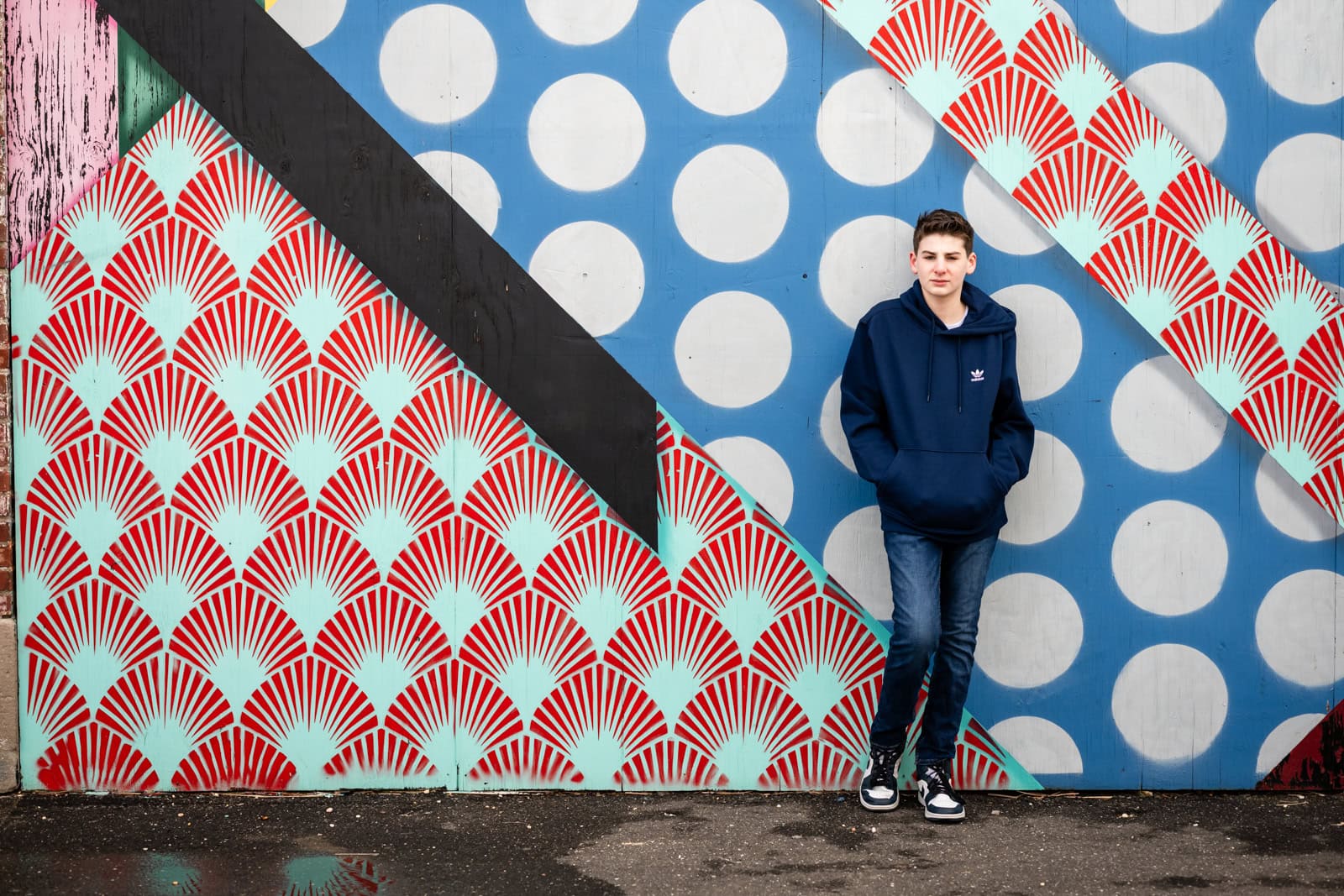 Person standing against colorful geometric mural wall.