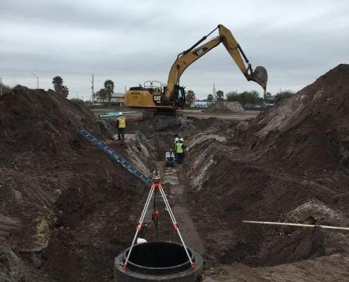 Excavation site with heavy machinery and construction workers for site development and infrastructure installation.