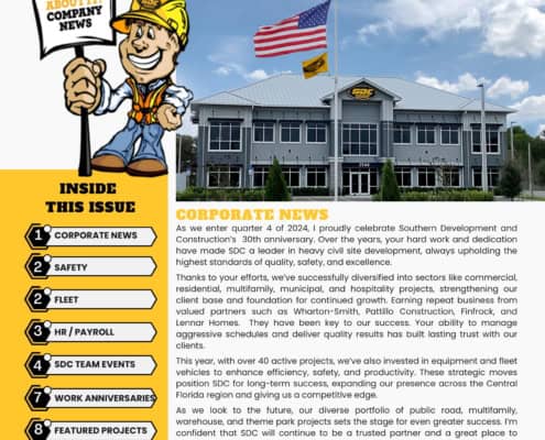 Broad Image of SDC construction company headquarters with American flag and company flags in front, under a blue sky.