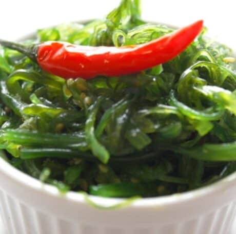 a bowl of seaweed salad with a red chili