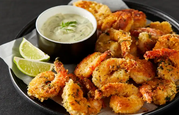 a plate of fried shrimp with a side of sauce