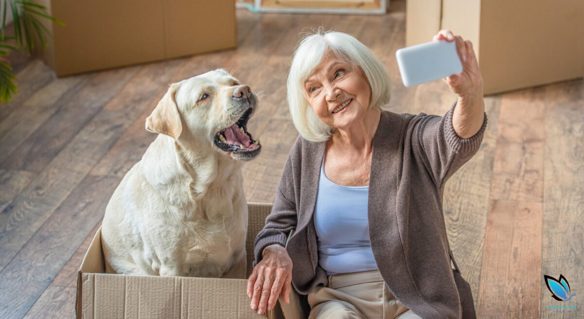 Senior woman with dog in a box taking a selfie and getting ready to move into an assisted living facility