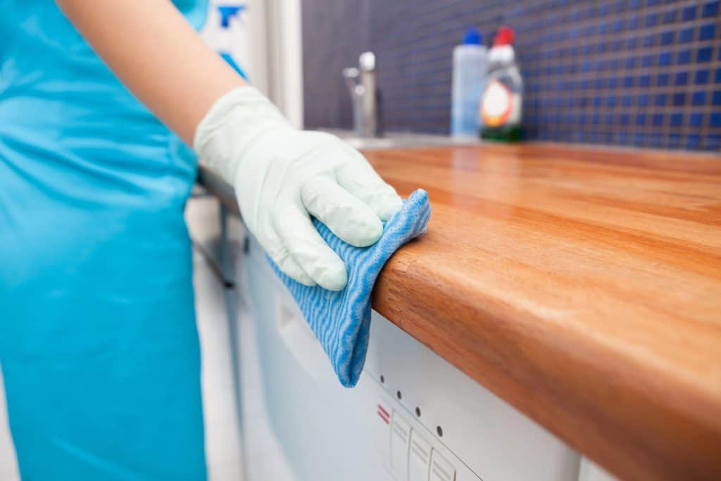 A lady cleaning a kitchen worktop with a cloth