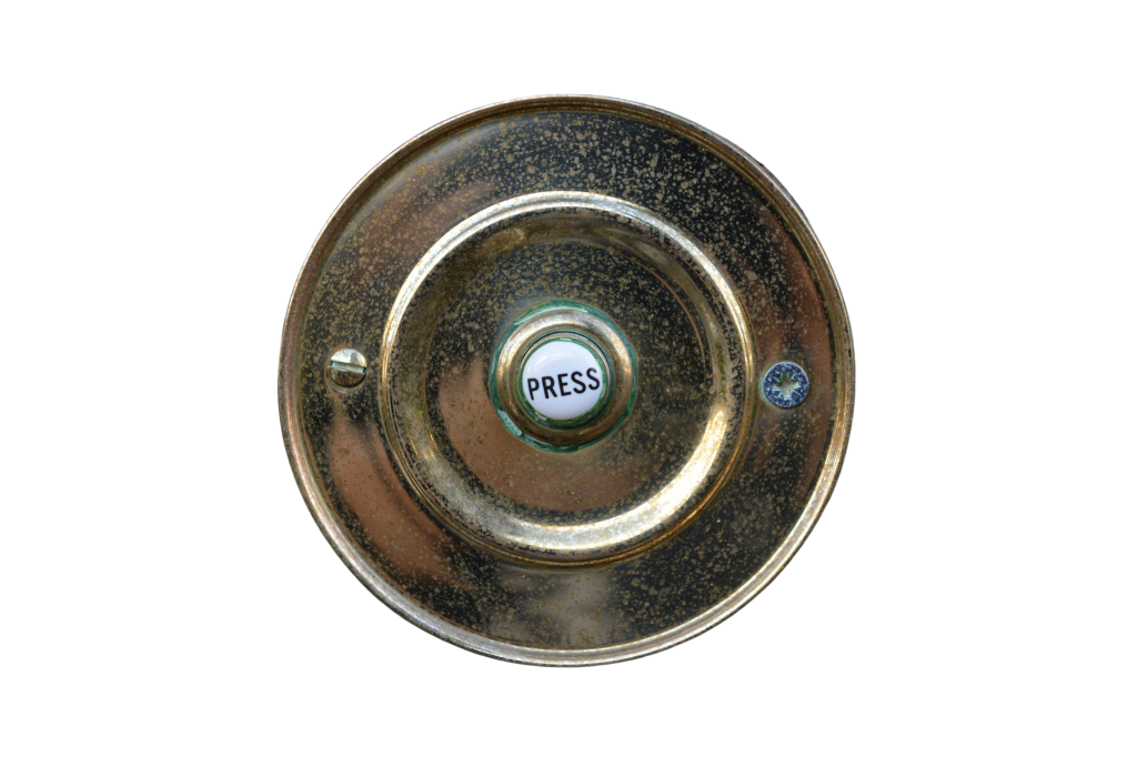A brass doorbell outside a house
