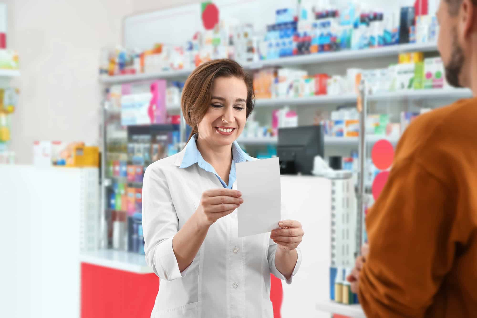 A man collecting medication from a pharmacist