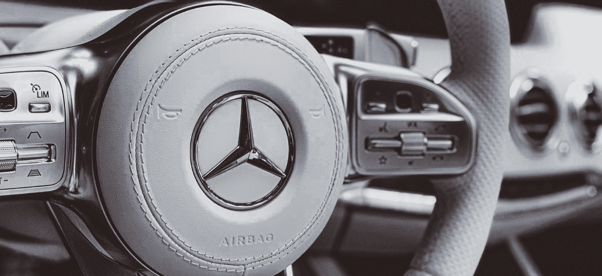 Mercedes-Benz car steering wheel with control buttons and logo.