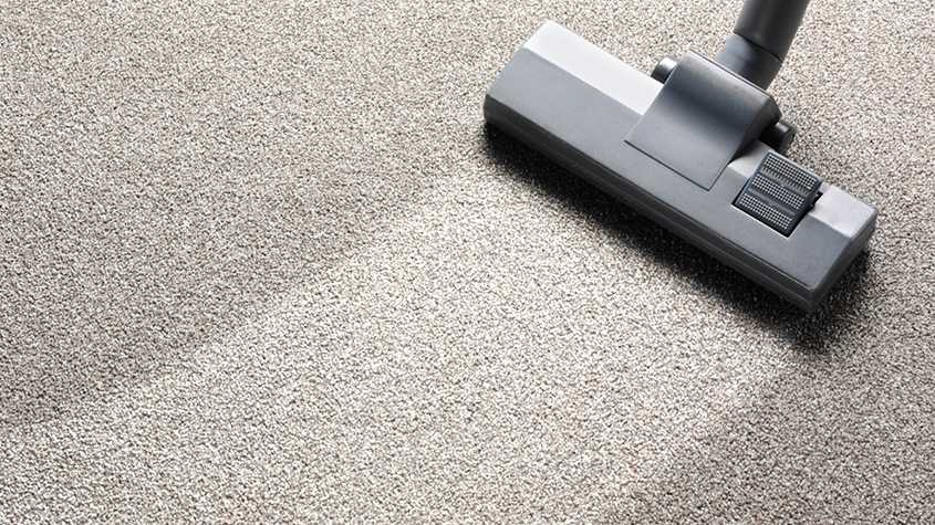 Carpet cleaning vacuum on beige carpet.