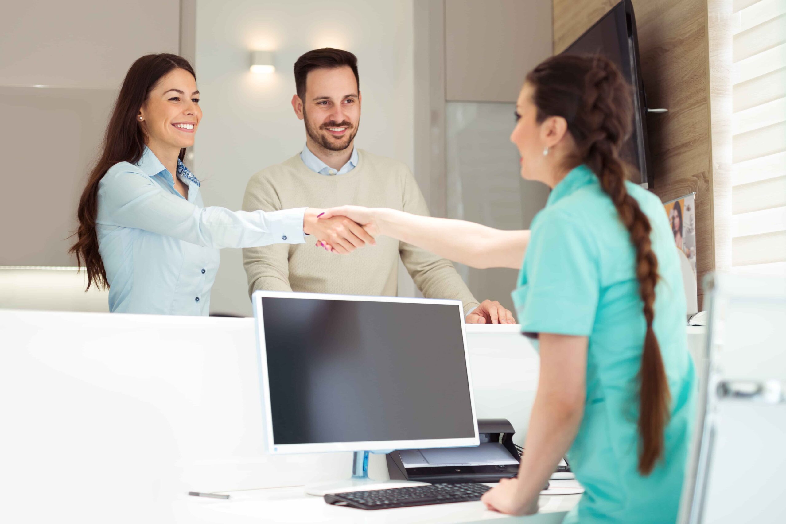 Friendly receptionist shaking hands with clients,